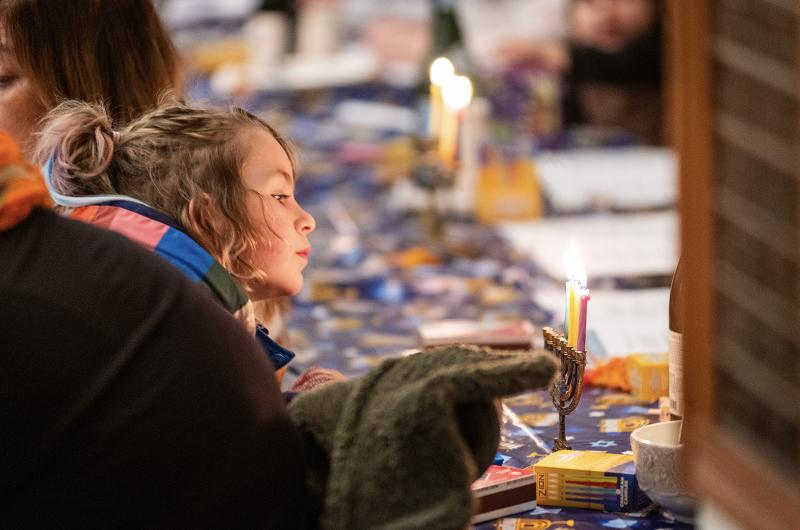 Young Hanukkah celebrant enjoys the light from the menorah.