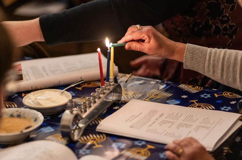 Attendees at The MV Hebrew Center Hanukkah celebration light their menorahs.